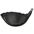 A golf club head features a smooth black surface with a metallic finish and alignment markings positioned for striking a golf ball during play on a golf course.