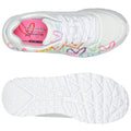 A white sneaker with colorful heart patterns on the side features a cushioned insole labeled Skechers Memory Foam showcasing a vibrant pink interior against a plain background.