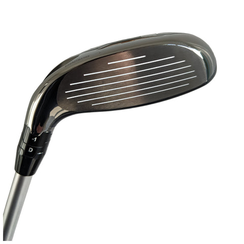 A golf club head lies on a white background displaying a smooth metallic surface with distinct horizontal grooves designed for striking a golf ball effectively. The club features adjustments for different angles.