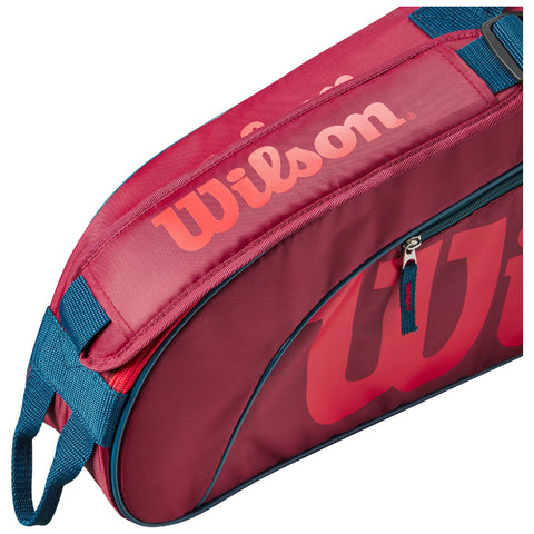 A red sports bag with a large Wilson logo is shown resting at an angle featuring a zippered section and a blue strap for carrying in various environments