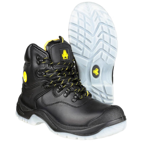 Black high-top safety boots with yellow accents sit upright next to a white outsole featuring a detailed tread pattern in a neutral background setting.