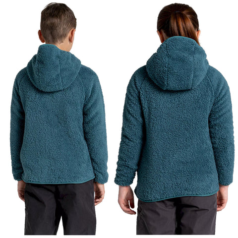 Two children wearing matching teal fleece jackets with hoods are standing back to back. The setting is a plain background emphasizing the clothing's texture and color.