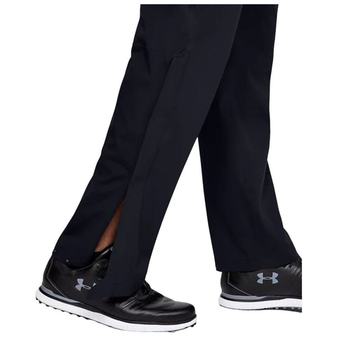 Black GOLF pants with side slits are being worn while walking in black GOLF shoes on a plain background, highlighting a casual and sporty appearance.