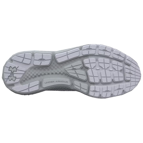 A white athletic shoe sole is displayed showing textured rubber patterns and grip features designed for traction while running or training on various surfaces with Under Armour branding visible.