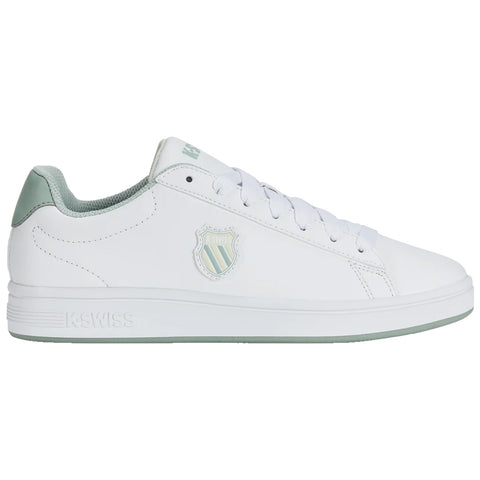 A white sneaker with a green accent features a logo on the side and is equipped with laces, presented on a plain background for focus on the shoe design.