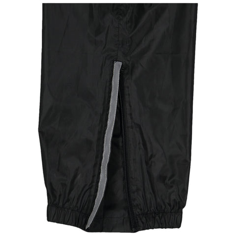 A pair of black outer pants is displayed with a gray zipper opening along the side and elastic cuffs at the bottom suggesting functionality for outdoor activities in various weather conditions.