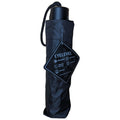 A black umbrella is standing upright with a carry strap and a tag attached. The umbrella is designed for functionality and durability with features like wind resistance and lightweight construction.