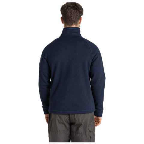 A person is wearing a navy blue pullover with a high collar facing away from the viewer in a simple, neutral background, suggesting an indoor or studio setting.