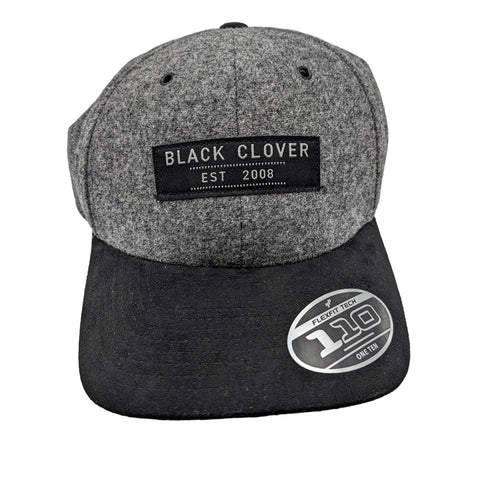 A gray and black baseball cap features a front patch labeled "BLACK CLOVER" and "EST 2008" with a circular sticker on the brim indicating "FLEXFIT TECH 110 ONE TEN"