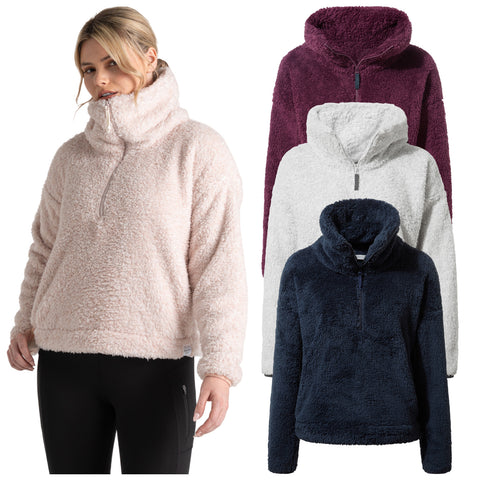 A woman stands wearing a soft, fuzzy pullover with a high collar and zip. Four color variations of the pullover are displayed behind her: pink, white, burgundy, and navy.