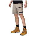 A person stands wearing khaki cargo shorts and yellow hiking boots. The individual holds their right hand slightly raised, suggesting readiness or engagement in an outdoor activity.