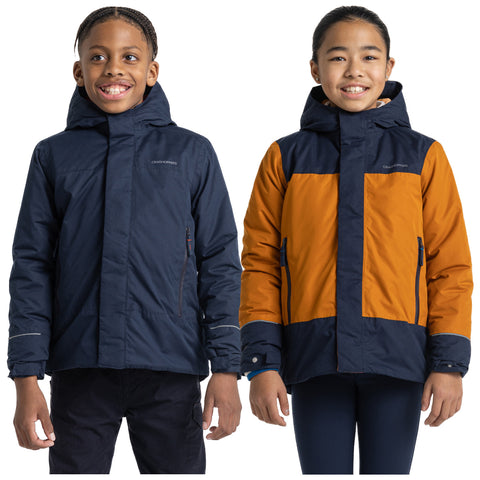 Two children stand side by side wearing jackets. One wears a dark blue jacket while the other wears an orange and blue jacket. They are smiling against a plain white background.