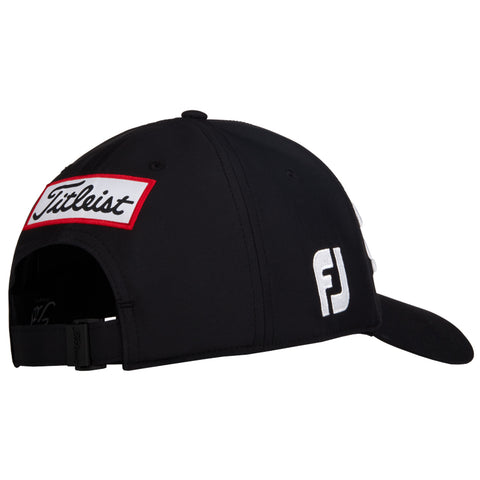 A black golf cap features a white brim and embroidered logos on the sides including Titleist in red and white and FJ in white against the black fabric.