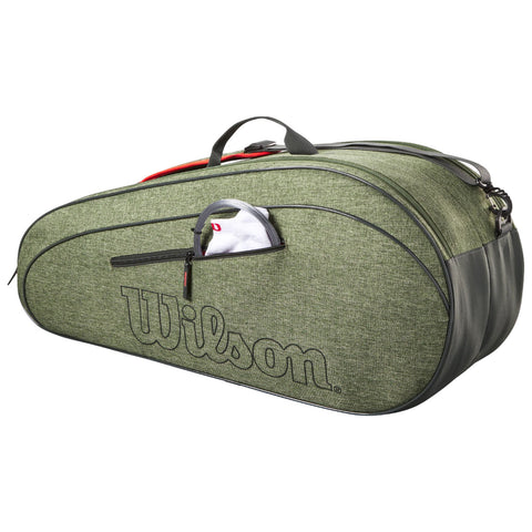 A green sports bag with a Wilson logo has a zippered pocket slightly open showing a folded item inside. It is designed for carrying sports equipment and is made from textured fabric.