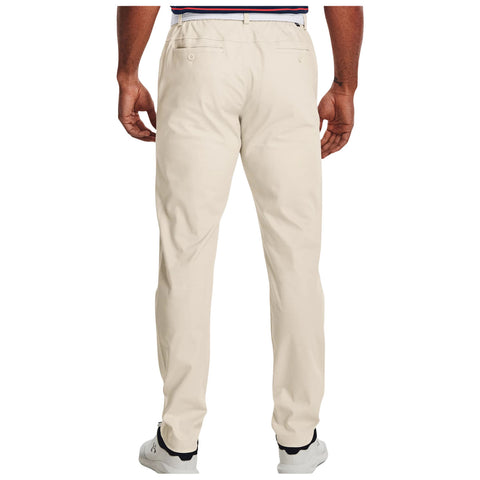 A person stands with their back facing the viewer, wearing light-colored golf chinos and white shoes against a plain background. Their left hand rests on their hip, emphasizing the garment's fit.