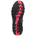 A black and pink shoe sole features deep treads and patterns designed for traction, resting against a neutral background, suggesting readiness for outdoor activities like running or hiking.