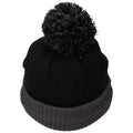 A black knitted beanie with a large pom-pom on top sits upright against a white background, showcasing its textured fabric and rolled cuff.