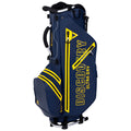 A golf bag in navy blue with yellow accents stands upright. It features multiple compartments for clubs and accessories, with handles for carrying, designed for easy transport to the golf course.