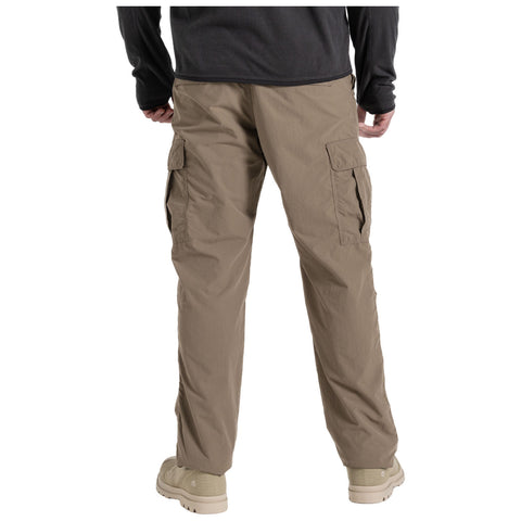 Beige cargo pants with side pockets are being worn by a person facing away. The environment suggests casual or outdoor wear, paired with light footwear.