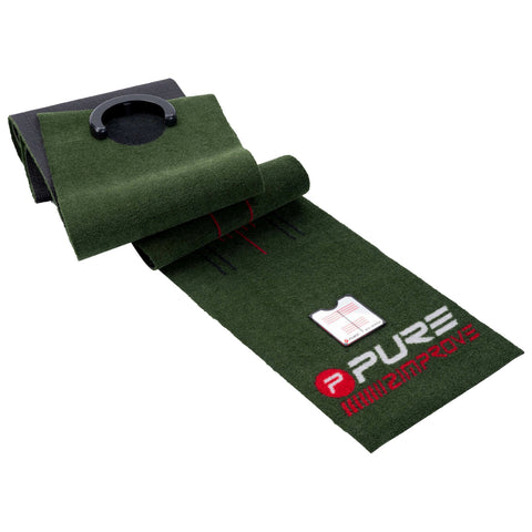 A green putting mat lies flat with a smooth surface featuring alignment guides and a hole at one end, designed for practicing golf putting indoors.