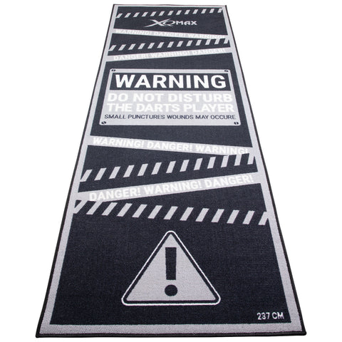 A long black and gray mat displays warnings about dart playing emphasizing not to disturb players and cautioning about potential small puncture wounds with a caution symbol at the bottom.