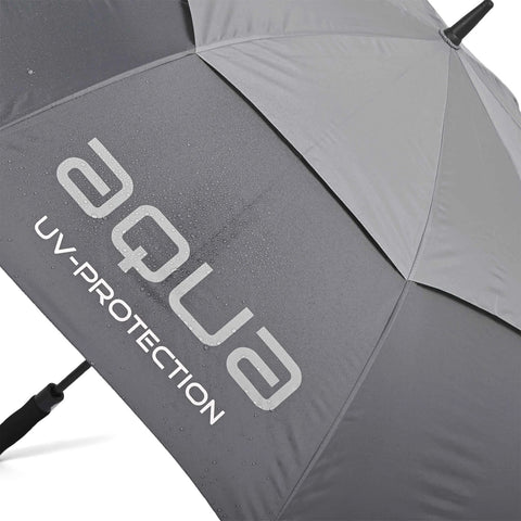 A gray umbrella with water droplets on its surface displays the text aqua UV-PROTECTION while lying flat on a surface indicating it's been recently used in wet conditions.