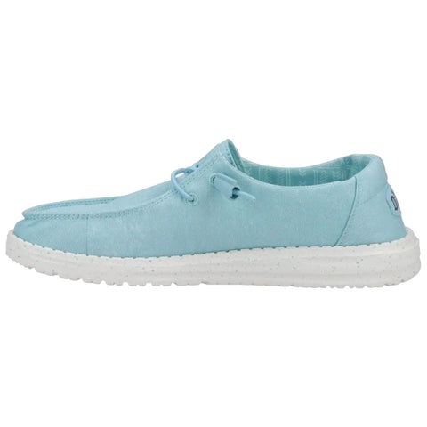 Light blue slip-on shoe rests horizontally displaying a smooth canvas upper with a flexible white sole set against a plain white background.