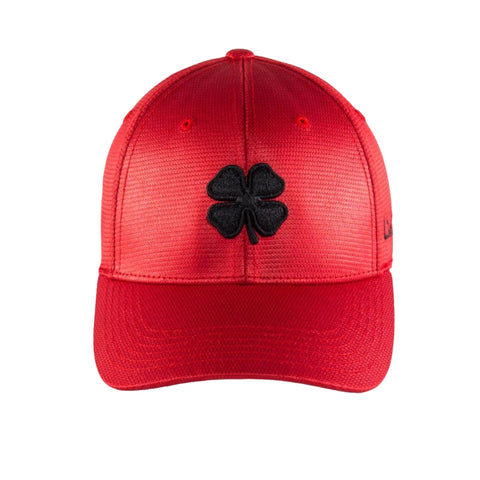 A red cap features a black four-leaf clover emblem on the front designed for casual wear and placed against a plain background.