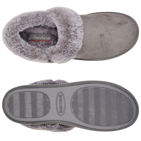 A grey slip-on slipper features a soft fur lining and memory foam interior providing comfort while the textured rubber sole offers grip suitable for indoor use.