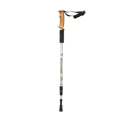 A trekking pole stands upright featuring a cork handle rubber grips and an adjustable aluminum shaft the context suggests outdoor activities like hiking or walking on uneven terrain.