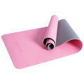 A yoga mat is partially unrolled with a pink side visible and a gray underside curling upwards offering a surface for exercise in a fitness environment.