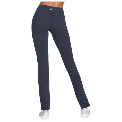 Navy leggings with a high waistband are being worn by a person facing away showing the back pockets while standing on a plain background with white shoes.