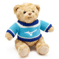 A plush teddy bear wearing a blue and white striped sweater sits upright with its arms slightly raised in a well-lit environment emphasizing its soft texture and friendly expression.