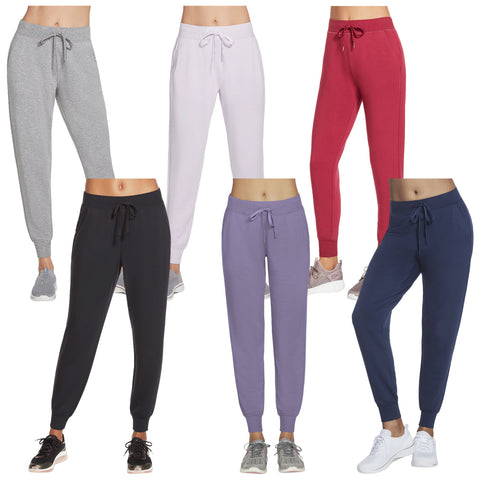 Six pairs of jogger pants in various colors are displayed. Each pair is shown on a mannequin waist-up, with drawstrings at the waist and fitted cuffs.