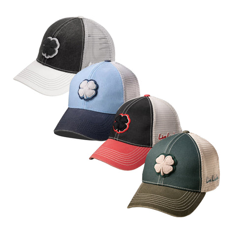 Four trucker hats are aligned horizontally featuring a four-leaf clover emblem on the front each in different colors black light blue black with red brim and dark green set against a plain background