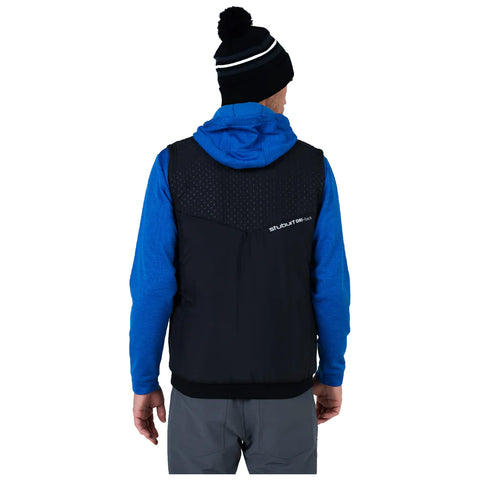 A person is wearing a blue hoodie under a black vest while facing away. They have a black beanie with a pom-pom on their head, suggesting cold weather.