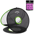 A collapsible golf net with a black mesh design and green trim sits open, intended for practice. The net includes a circular target hole and is accompanied by a bag of pink balls.