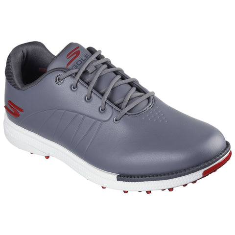 A grey golf shoe features a smooth surface with red accents and a textured sole equipped with spikes for traction during play stored against a plain background.