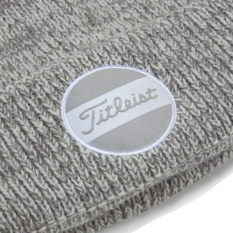 A knitted gray beanie features a circular logo with the name Titleist displayed in cursive against a background of two horizontal stripes in light gray and white.