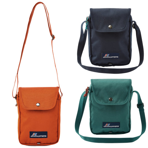 Three small shoulder bags are displayed in orange green and dark blue each with a flap closure and an adjustable strap against a plain background showcasing their simple functional design.