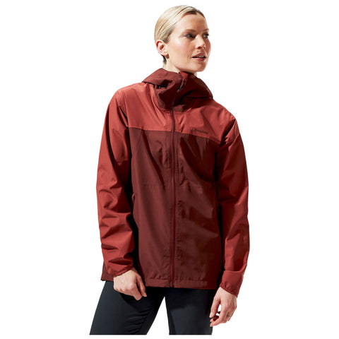 A woman is wearing a red waterproof jacket with a hood and a zip closure while looking slightly to the side in a neutral background suitable for outdoor activities.