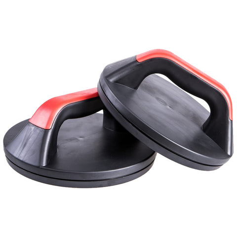 Two black workout push-up handles with red grips sit on a flat surface. They are designed to aid in strength training by providing better wrist alignment during push-ups.