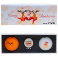 A festive golf ball set includes an orange ball with reindeer designs a white ball featuring a Santa face and a ball marker with a Santa graphic in a decorative box.