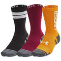 Three pairs of socks display a black pair with white stripes a burgundy pair and an orange pair featuring the logo Under Armour positioned against a plain white background.