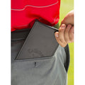 A black leather wallet with the Callaway logo is partially pulled from the back pocket of gray trousers while a hand grips its edge against a background of grass, suggesting an outdoor setting.