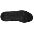 A black athletic shoe sole lies flat displaying its tread pattern designed for grip and traction in various environments such as sports courts or outdoor terrains