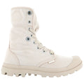 A beige high-top boot made of canvas with a textured surface featuring metal eyelets and laces is positioned upright against a plain white background. The sole is rugged and designed for traction.