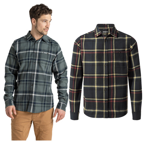 A man is modeling two distinct plaid flannel shirts one in green and dark blue tones and the other in black with yellow and red accents showcasing casual style in a neutral background.