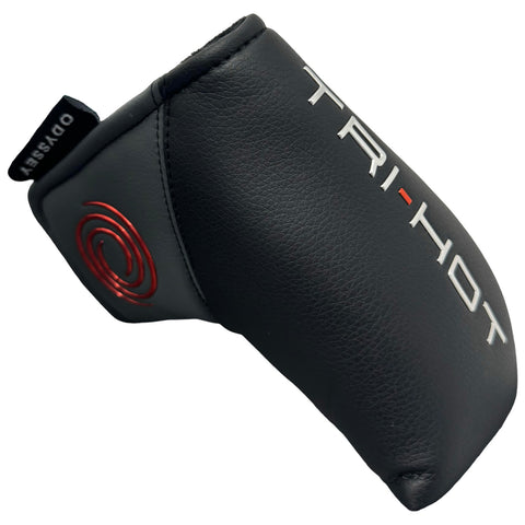 A black leather golf putter cover rests at an angle featuring the text TRI-HOT in white and red markings with a spiral logo displayed in red on the side.