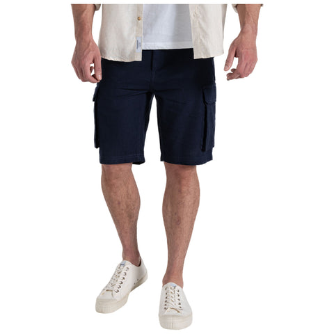 A person stands wearing dark cargo shorts and white sneakers. Their hands are relaxed at their sides. They are in a neutral setting with no distinct background details visible.